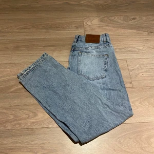 Blå jeans från Grunt - Säljer ett par klassiska blå jeans från grunt med en avslappnad passform och rå kant vid bensluten. De har en traditionell femficksdesign och en läderpatch baktill. Perfekta för en casual look. Passar XS/XSS