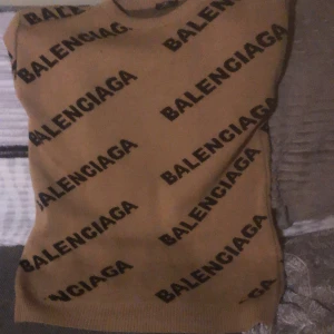Beige långarmad topp från Balenciaga - Snygg beige långarmad topp från Balenciaga med svart logotypmönster över hela plagget. Perfekt för en trendig look.