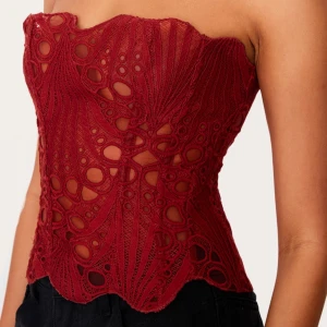 Korset topp - Snygg röd korsett med spetsdetaljer och ett unikt mönster. 