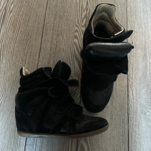Isabel marant skor - Snygga svarta isabel marant skor med hög design och kardborreband. Skorna har en unik stil med vadderad ankel och en robust sula. Perfekta för en trendig look. Skor är i använt skick men har mycket kvar att ge💞där är slitningar i skon som ni ser på bilden, kardborrebanden överst på skon är även lite slitet men skorna går att använda som vanligt!🤩 original sulan saknas😇
