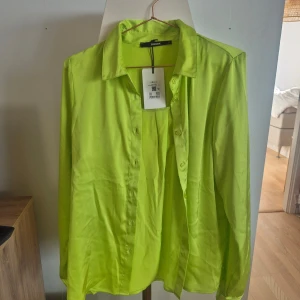 Helt ny! Neongul/grön skjorta från BikBok - Säljer en cool neongul/grön skjorta från BikBok. Skjortan har långa ärmar och knappar framtill. Perfekt för att lysa upp garderoben med en färgklick. Passar bra till både jeans och kjol. 🌟 Nypris 399kr