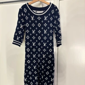 Mörkblå mönstrad klänning - Snygg mörkblå klänning med vitt mönster och trekvartsärmar. Klänningen har en rund halsringning och ett elegant mönster som ger en lyxig känsla. Perfekt för att sticka ut med stil. Den är veldigt stretchig.