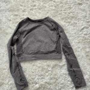 Grå croppad topp från relode stl M - Snygg grå croppad tröja från Relode med långa ärmar och meshdetaljer på sidorna. har hål för tummarna längst ner på ärmarna, använt max 2 gånger, köparen betalar frakt☺️