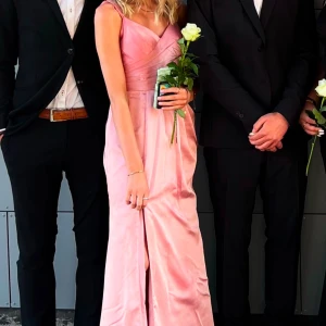 Rosa satin klänning  - Säljer min rosa balklänning i satin💗Den har smala axelband med omlottdesign, justerbara axelband och inbyggd bh. Perfekt för studentbalar nu till sommaren eller till andra festliga tillfällen! Köpt från JJ house 2023 för 1400kr, och har endast använt den en gång på min bal i somras. Hör av er vid frågor eller mått!💞