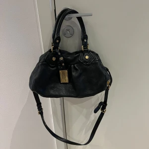 Marc Jacobs väska  - Mått: ca 30 cm bred och 18 cm höjd🩷Snygg svart handväska från Marc by Marc Jacobs i skinn med justerbar axelrem och handtag. Jätte fint skick, inga större skador. Skriv för frågor😊