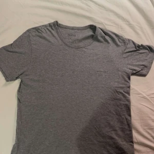 Grå t-shirt från Hugo Boss - Säljer en stilren grå t-shirt från Boss. Den har en klassisk passform med korta ärmar och rund halsringning. Bra skick.