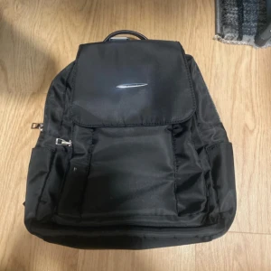 Svart ryggsäck med dragkedja - Säljer en stilren och funktionell svart ryggsäck. Denna ryggsäck är perfekt för skolan, resor eller dagligt bruk. Den har flera fack för att hålla dina saker organiserade och en bekväm passform för långvarig användning.  Oavsett om du ska till gymmet, skolan eller på äventyr, är denna ryggsäck ett utmärkt val. Passa på att skaffa en kvalitetsryggsäck till ett bra pris!