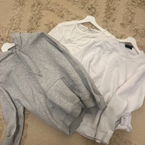 Pack med kläder - Säljer en grå hoodie med känguruficka och dragsko i huvan samt en vit sweatshirt och en vit tight tröja. Perfekta för en avslappnad stil. Båda tröjorna har långa ärmar och är gjorda i mjukt material. Olika märken 🟥ops den gråa hoddien är såld! Plus den vita tighta!🟥