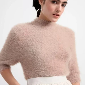 Beige fluffig tröja - Säljer en supermjuk och fluffig beige tröja med trekvartsärm. Perfekt för att hålla sig varm och stilren under kyligare dagar. Tröjan har en croppad passform som ger en modern look.  köpte för 500 .