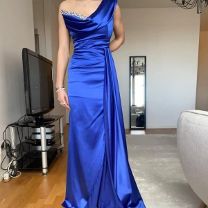 Balklänning - Elegant blå långklänning i satin i gott skick. Man kan ha det tunna bandet på olika sätt som man ser på bilderna. Köpt för ca 3000kr💓(säljer även mina systrars balklänningar) Pris går att diskutera 