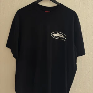 Svart t-shirt med tryck från Corteiz - Tshirt från Corteiz med tryck både fram och bak. T-shirten är storlek L och har avslappnad passform. Säljs pga för stor för mig. Knappt använd, pris kan diskuteras. Äkthets bevis finns.