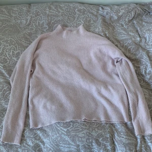 Ljusrosa ribbad tröja från Vero Moda. Aldrig använd  - Säljer en ljusrosa ribbad tröja från Vero Moda. Tröjan har en hög krage och långa ärmar, perfekt för kyligare dagar. Den är mjuk och bekväm, vilket gör den till ett utmärkt val för både vardag och mysiga stunder hemma.