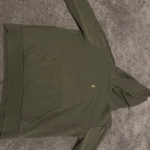 Olivgrön hoodie från Ralph Lauren - Säljer en stilren olivgrön hoodie från Ralph Lauren. Tröjan har en klassisk design med en känguruficka framtill och en liten broderad logga på bröstet. 