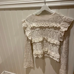 Beige spetsblus från Zara - Säljer en vacker beige spetsblus från Zara med volangdetaljer. Blusen har långa ärmar och ett intrikat spetsmönster som ger en romantisk känsla. Perfekt för att lyfta vilken outfit som helst.