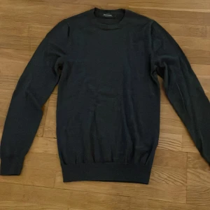 Merinoull tröja - Säljer en stilren mörkgrå sweatshirt i merinoull från Dressmann. Den är i storlek S och är den bra skick. Det finns en deffekt på armen som man inte tänker på men man kan se den på bild 4. Hör av er vid frågor.