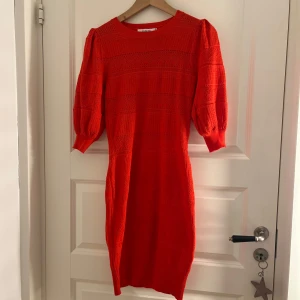 Röd stickad klänning - Säljer en snygg röd stickad klänning med trekvartsärm och en figurnära passform. Perfekt för att lysa upp garderoben med sin klara färg. Klänningen har ett diskret mönster som ger den en extra touch. Nypris 499 kr, aldrig använd.