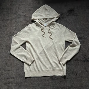 Stickad merinoull hoodie - Säljer en stilren beige hoodie från Ahlquist Clothing. Den är helt oanvänd och i bästa skicket.  Nypris 999kr. Tröjan har en klassisk design med huva. Perfekt för en avslappnad look. Storleken är xxs men passar även xs
