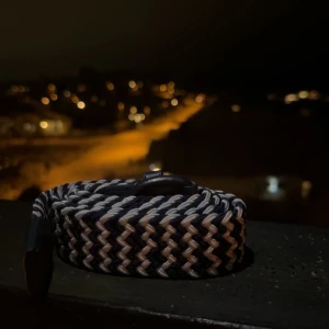 Flätat bälte i marinblå och vit - Snyggt flätat bälte i svart och beige med ett coolt mönster. Perfekt för att ge din outfit en extra touch. Bältet har en klassisk design och passar till många olika stilar.