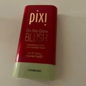 Pixi On-the-Glow Blush - Säljer en Pixi On-the-Glow Blush i en praktisk stickform. Den har en röd nyans och är perfekt för att ge kinderna en fräsch och naturlig glöd. Förpackningen är kompakt och lätt att ta med sig.