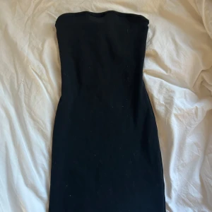 Svart axelbandslös klänning - Snygg svart bandeau klänning som är lite figur sydd och sitter jätte fint! Utan axelband och mini klänning. Aldrig använd endast testad 