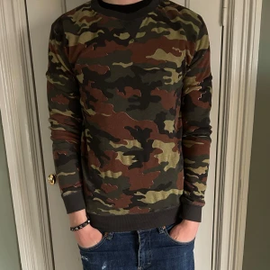 Camouflage tröja - Säljer en unik skön tröja med camouflage mönster i gröna och bruna nyanser. Tröjan är perfekt för en avslappnad stil. Tveka inte på att kontakta mig vid minsta fundering eller eventuella frågor