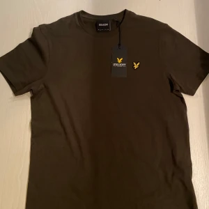 Oliv grön t-shirt från Lyle & Scott - Hej! Säljer nu min snygga lyle scott tröja pågrund av att den va för stor och kunde intr lämna tillbaka den. Fick den i present och är bara använd en gång för att testa. Hör av er om ni har några frågor!