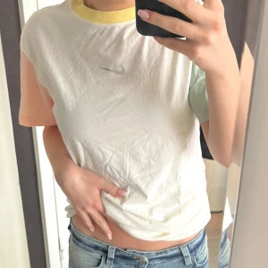 Vit t-shirt från Nike - Säljer en vit tshirt från Nike med lång passform och ärmar i olika färger. Den går antingen att använda som klänningen eller vika upp och använda den som vanlig tshirt! Mycket bra skick utan defekter! 