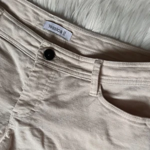 Ribbade ljusbeige byxor - Ljusbeige byxor med lent och ribbat tyg och design på bakfickorna. Vida i benen och lågmidjad passform. Dessa är för stora på mig då jag brukar ha 38-40🤍(obs behöver strykas)