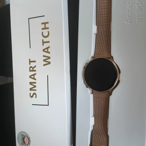 Smartklocka med utbytbara armband - Helt ny smartklocka med rund urtavla och två utbytbara armband. Ett armband är i roséguld mesh och det andra i rosa silikon. Perfekt för att matcha olika kön, stilar och tillfällen. Medföljer laddare. 