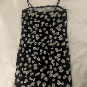 Svart blommig klänning från Shein - Söt svart klänning med vita blommor från Shein. Den har smala axelband och ett blommigt mönster som ger en somrig känsla. Perfekt för varma dagar eller en avslappnad stil. 🌼storlek 134/9years