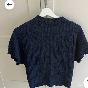 Mörkblå topp med struktur - Säljer en mörkblå topp med en unik strukturerad yta. Toppen är använd ett fåtal gånger! Tröjan är i storlek M men passar mig som brukar ha xs/s i tröjor💕för bättre bilder är det bara att höra av sig💕