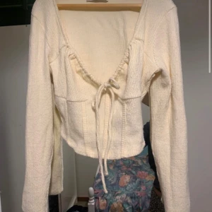 Vit ribbad tröja från Bershka strl S  - Säljer en stilren vit ribbad tröja från Bershka. Tröjan har en v-ringad design med knytning framtill och långa ärmar. Perfekt för en trendig look.