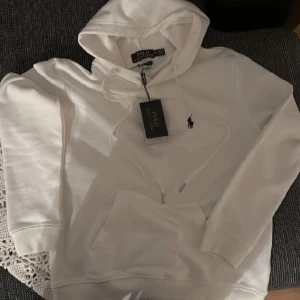 Vit hoodie från Ralph Lauren - Tja, Jag säljer en fet tröja från ralph lauren. Köpte den åt min brorsa men storleken passade inte så säljer vidare den. Den är i storlek M men är liten i storlek. Den är i perfekt skick och helt ny då lappen fortfarande är kvar. Vill bara ha den såld, levererar snabbt. Priset är inte hugget i sten