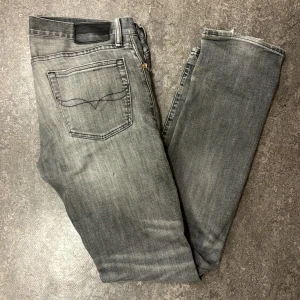 Grå jeans från Polo Ralph Lauren - Säljer ett par grå jeans från Polo Ralph Lauren i modellen Varick Slim Straight. De har en snygg slitning och är i en slim passform. De är i storlek 32/34.