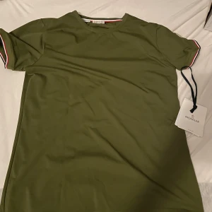 Moncler t-shirt  - Tjo säljer min army Green Moncler t shirt i storlek L!! Säljer den för att jag inte använder den ofta och är i nöd av pengar😅😅