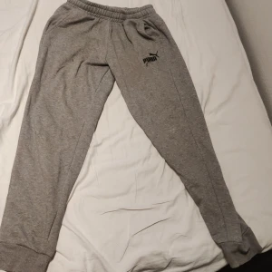 Puma Mjukisbyxor - Gråa Puma Mjukisbyxor använt många gånger, 1litet hål på båda knän, och en reva vid Puma loggan som är ihopsydd, byxorna är svagt avfärgade med färgen röd pga feltvättat.