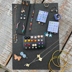 Färgglada smycken ALLT INGÅR DU FÅR ALLT PÅ BILDEN - Ett härligt urval av smycken med massor av färg och stil! Här finns örhängen i olika former och färger, inklusive stjärnor och kors. Halsband med blommor och fjärilar, samt armband med färgglada pärlor. Det finns också ringar i olika stilar och färger, inklusive en cool blå ring. Perfekt för att liva upp vilken outfit som helst!