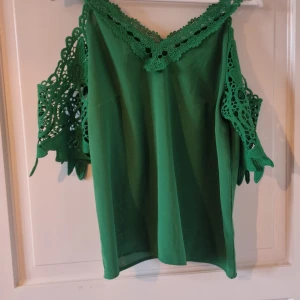 Grön blus med spetsdetaljer från Shein - Säljer en snygg grön blus  från Shein i storlek L. Blusen  har vackra spetsdetaljer vid ärmarna och halsen, vilket ger den en romantisk touch. Perfekt för både vardag och festliga tillfällen. 💚