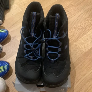 Svarta boots från Ecco - Säljer ett par svarta Ecco boots i mycket bra skick. De har blå snörning och en robust sula perfekt för höst och vinter. Skorna är bekväma och passar bra för utomhusaktiviteter.