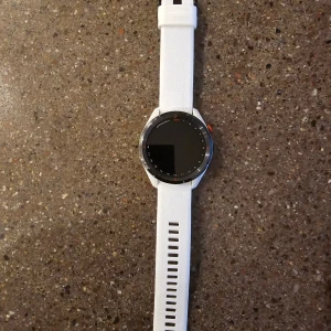 Vit smartklocka med silikonarmband - Garmin approach s62. Säljer en stilren vit smartklocka med ett bekvämt silikonarmband. Klockan har en rund urtavla med en modern design och är perfekt för både vardag och träning. Den har en slät yta och justerbart band för bästa passform.