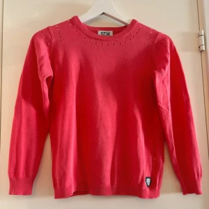 Röd tröja från CRW - Säljer en snygg röd tröja från CRW i storlek 146/152. Tröjan är i mycket bra skick och har ett diskret hålmönster längs halsringningen och ärmarna. Perfekt för höst och vår, och den är supermjuk och bekväm. Passar både till vardags och lite finare tillfällen. 🌟