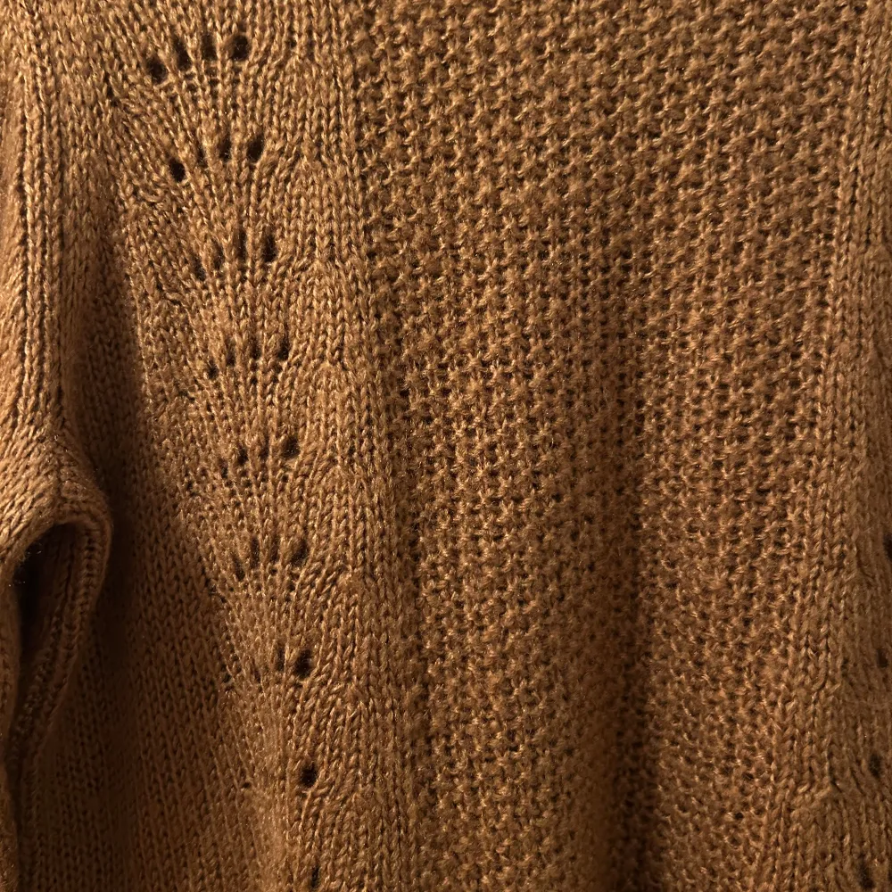 Säljer en mysig brun stickad tröja med ett fint hålmönster längs ärmarna och framstycket. Perfekt för höst och vinter, den har långa ärmar och en bekväm passform. Tröjan är i mycket bra skick och passar perfekt för kyliga dagar. Helt ny men utan prislapp 🧶🍂. Neuletakit & Villapaidat.