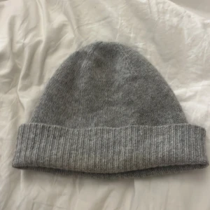 Grå stickad kashmir mössa - Säljer en mysig grå kashmir mössa i bra skick. Perfekt för kalla höst- och vinterdagar. Den har en ribbad kant som ger en skön passform. Enkelt och stilrent plagg som passar till det mesta. Håll huvudet varmt och stilen på topp! Använd en del men ser fortfarande jättebra ut och inga slitningar!💞