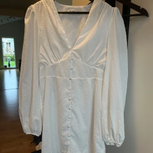 Studentklänning - Säljer nu min fina studentklänning från NAKD. Den är i storlek 38 och är använd vid ett tillfälle, min student. Den passar även väldigt bra till midsommar. Ballongärmar och knappar i mitten, där finns även en dragkedja på ena sidan (bild 5). Nypris 599kr💗