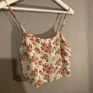 Säljer ett tunt superfint blommigt linne. Perfekt för sommardagar med sitt lätta och luftiga material. Linnet har smala axelband och ett härligt blommönster i rosa och grönt på en vit bakgrund. Passar perfekt till jeans eller shorts för en avslappnad look. (PM OM DU VILL HA FLER BILDER)