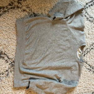 Grå sweatshirt från H&M - Mysig grå sweatshirt från H&M i storlek S. Tillverkad av 72% bomull, 23% polyester och 5% viskos. Den har en klassisk rund hals och långa ärmar. Perfekt för höst och vinter!