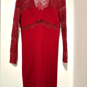 Röd spetsklänning  - Säljer en elegant röd klänning med vacker spetsdetalj och lång ärm. Klänningen har en figurnära passform och en djup v-ringning. Perfekt för festliga tillfällen! 💃