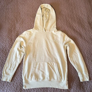 Beige hoodie från Unknown - Säljer en stilren beige hoodie i storlek 158/164 för åldern 13/14 år. Den har en klassisk känguruficka och en bekväm huva. Perfekt för vardagsbruk och håller dig varm under kyliga dagar. Passar bra till både jeans och mjukisbyxor.