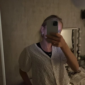 Vit blus med broderade detaljer - Säljer en söt vit blus med broderade detaljer och knappar framtill. Blusen har korta ärmar och en luftig passform, perfekt för sommardagar. Den är i mycket bra skick och passar både till vardags och festliga tillfällen.suoer fin att ha över ett linne