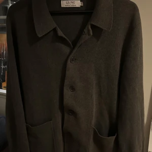 Grå overshirt från Ljung - Säljer en stilren grå kappa från Ljung i mycket bra skick. Den har en klassisk krage och knappar framtill. Perfekt för höst och vår, med en normal passform som funkar till de flesta outfits. Kappan är långärmad och gjord i ett mjukt material som känns skönt mot huden.